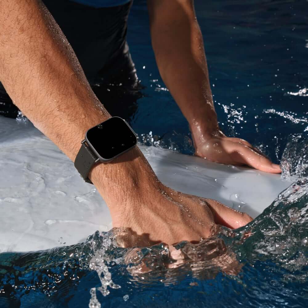 Person wearing Xiaomi Redmi Watch 5 Active while surfing, showcasing its sleek design and water resistance.